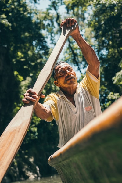 In a gray collar T-shirt man carrying a brown sticks
